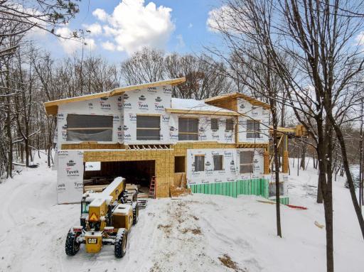 Framing nearly complete on this Upscale Rustic Modern home, designed with dramatic rooflines, black window packages, and a future walnut garage door to anchor the modern-warm exterior palette.