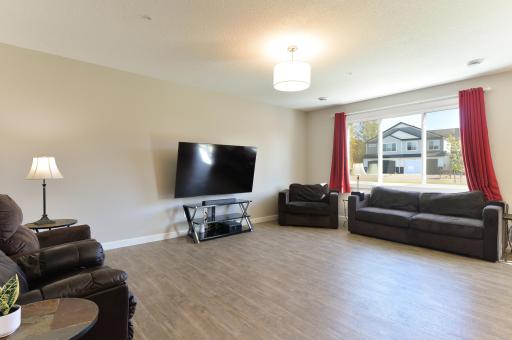 The main level living room is open and bright with hard surface flooring and an oversized window that lets in plenty of natural light.