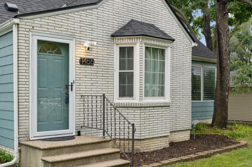 Concrete sidewalk greets you to the front entry door with fresh paint and new storm door.
