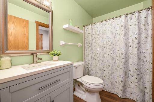 Updated main-floor bathroom featuring modern vanity, fresh flooring, and paint