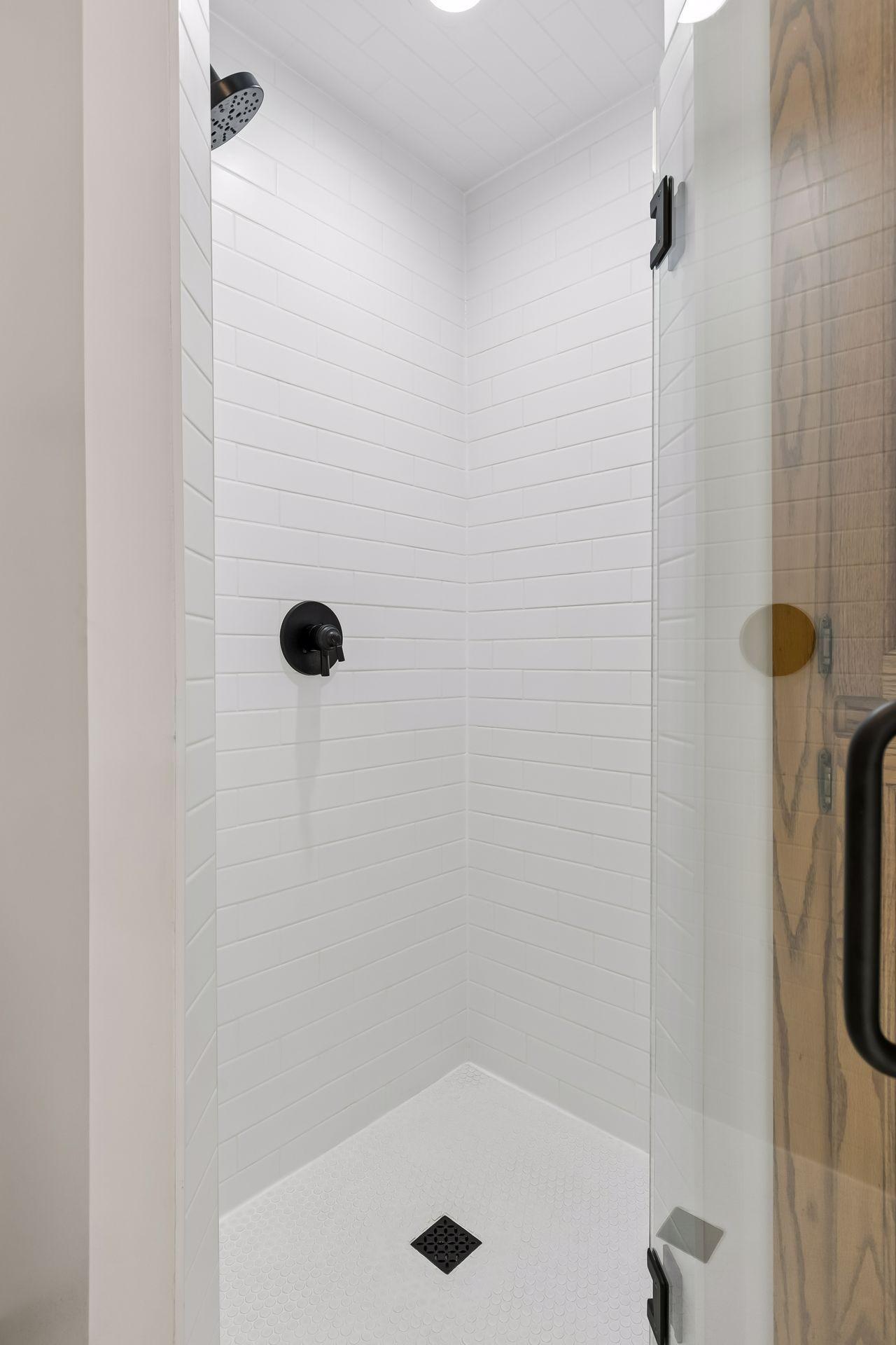 Beautiful brand new (2026) subway tiled shower with glass door and black fixtures.