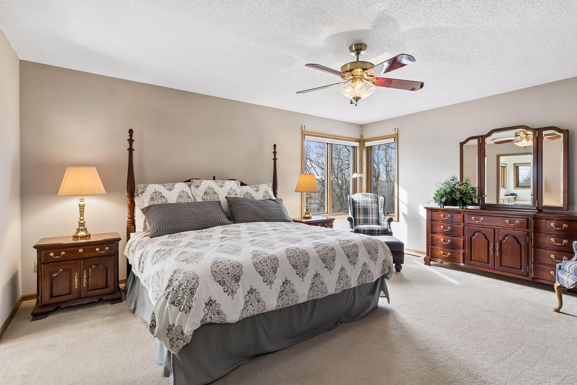 Impressively large owner's suite with windows on two walls, a ceiling fan.