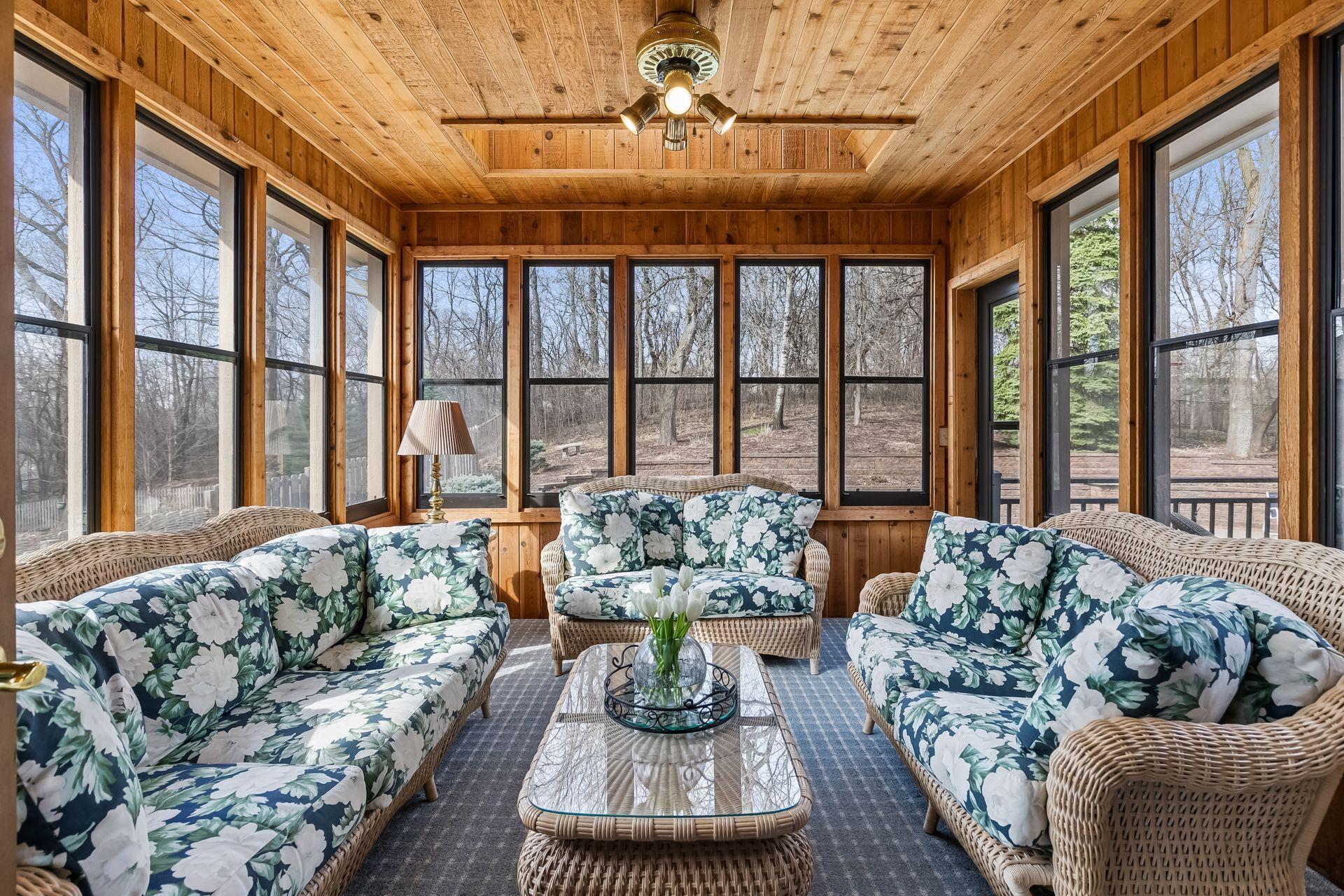 Cedar-lined three-season sunroom surrounded by windows with deck access