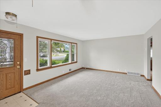Main floor living room with new carpet and big picture window for tons of natural light.