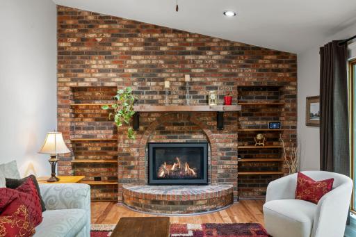 Gas fireplace flanked by bookcases and brick surround