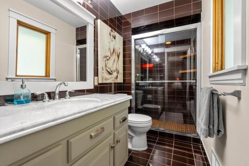 Primary 3/4 bath with tiled floor and shower surround, marble vanity top