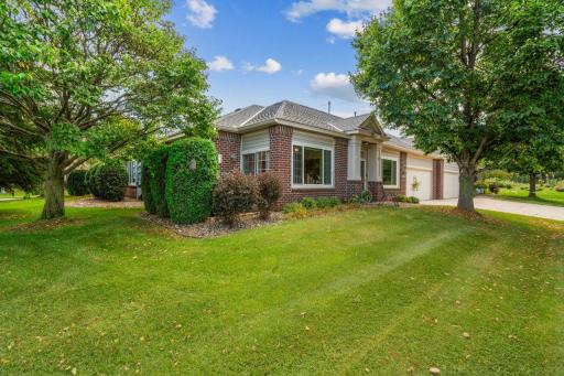 Mature trees and manicured shrubs frame the property, creating both shade and privacy, while the expansive lawn adds to its welcoming atmosphere.