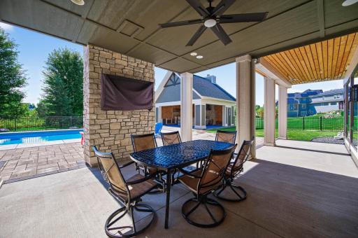 The covered patio extends entertaining with a ceiling fan and TV, while beautiful landscaping and a full irrigation system complete the setting.