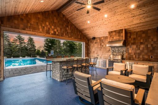 Enhanced by a spectacular pool house with soaring cedar ceilings, an expansive island, wood-burning fireplace, gas grill with vented hood, beverage fridges, powered screens, and built-in speakersâthis space rivals the finest resorts.