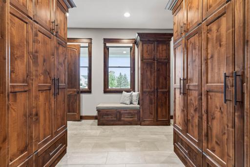 The adjacent mudroom is thoughtfully designed for everyday convenience, featuring lockers, bench seating, counter space, and a walk-in closet, with direct access to the heated three-car garage.