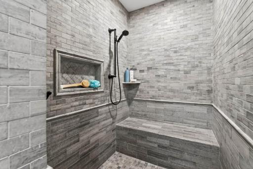 A spacious walk-in tiled shower with bench seating adds comfort and function to the space.