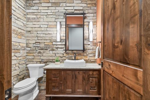 Nearby, a powder room with dramatic stone walls makes a bold design statement.