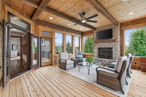 The living space extends into a three-season insulated sunroom, where cedar walls, ceilings, and floors pair with a cozy gas fireplace to create a welcoming retreat.