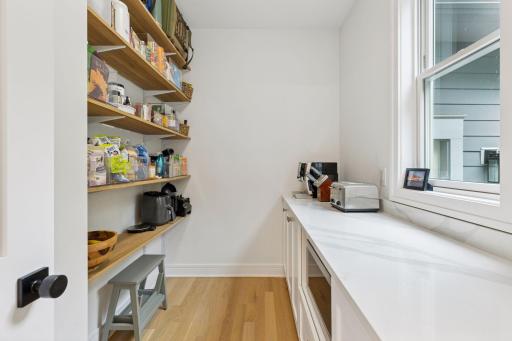 This incredible walk-in pantry boasts a 9-foot counter for prep space or small appliance storage, loads of cabinetry, and floor-to-ceiling shelving.