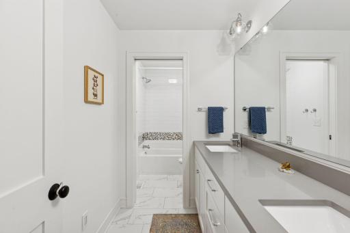Upper level hall bathroom features a dual-sink vanity with dedicated reverse-osmosis drinking water faucet, and delightful custom tilework.