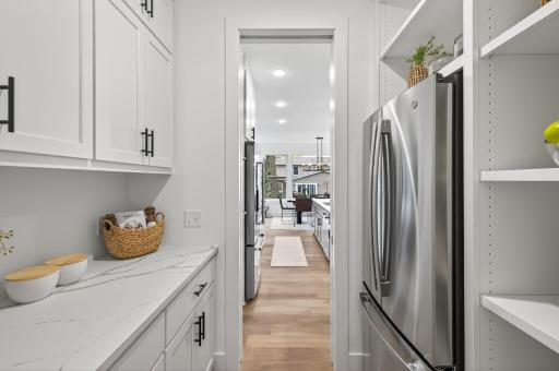 A thoughtfully designed walk-through butlerâs pantry features custom cabinetry and a full-size refrigerator, offering both beauty and function for effortless entertaining.