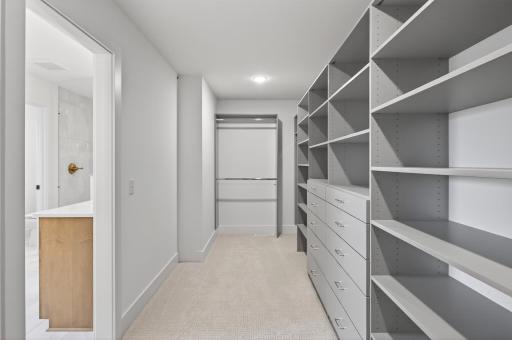 The expansive custom walk-in closet offers exceptional organization and elegance, featuring thoughtfully designed storage solutions.