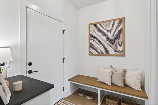 A practical mudroom off the garage offers a seamless transition into the home, featuring built-in storage, durable flooring, and ample space for coats & shoes.