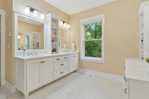 The primary bath showcases heated tile floor, a raised dual vanity, built in make up counter...