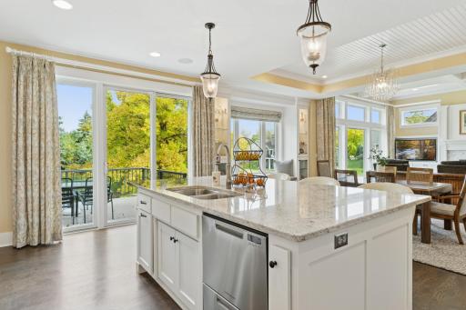 The kitchen features an oversized center island, stainless appliances, quartz counters, tile backsplash and walk-in pantry