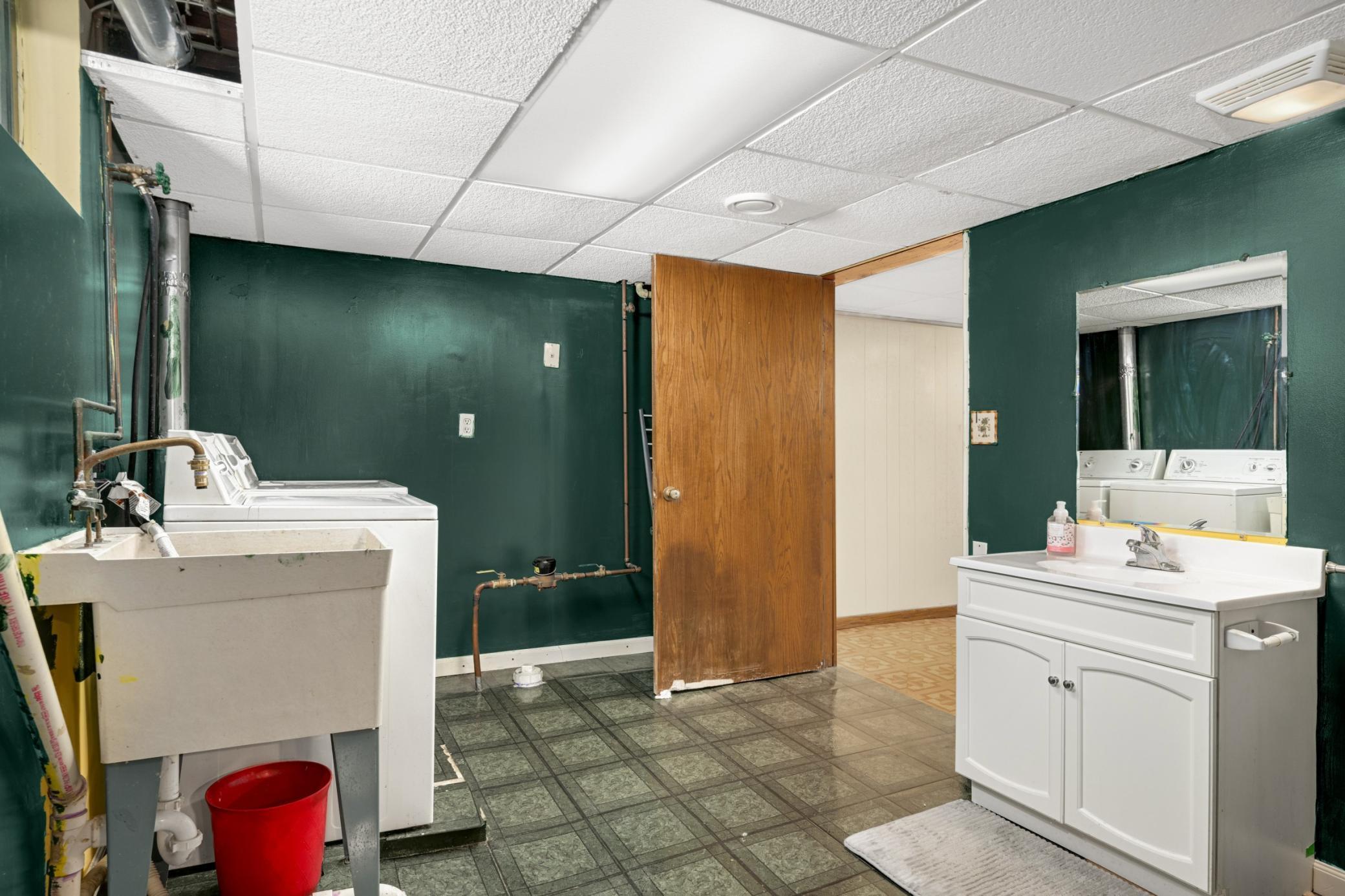 Lower bath/laundry with bold dark walls and durable tile flooring