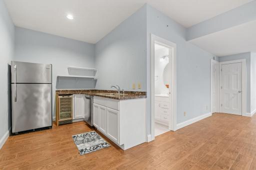 Basement wet bar featuring full-sized fridge, beverage cooler and dishwasher.