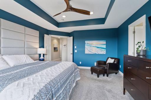 This space showcases a tray ceiling for added architectural charm, a large windows, and a ceiling fan for year-round comfort.