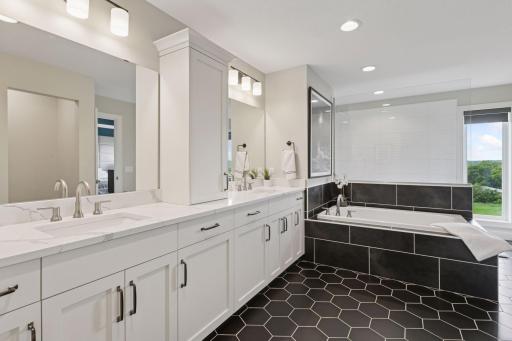Another exceptional space! This ensuite features heated tile floors, a large tub, a separate walk-in shower, and an expansive vanity with abundant storage and dual sinks for added convenience.
