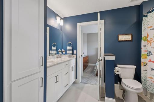This Jack-and-Jill bathroom offers a spacious vanity with ample storage and dual sinks.
