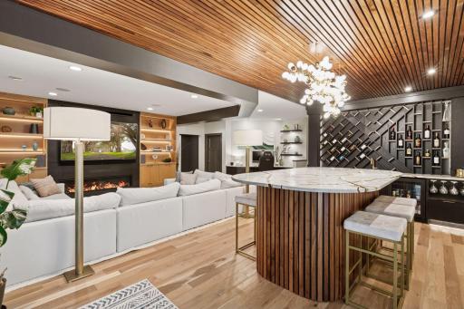 Spectacular open-concept lower level with stunning wood slat ceilings, designer wet bar and bar table, cozy fireplace seating area and a seamless flow - perfect for entertaining!