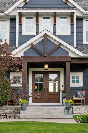 Striking front entrance with custom timber frame details, elegant double doors, and welcoming covered porch showcasing exceptional curb appeal.
