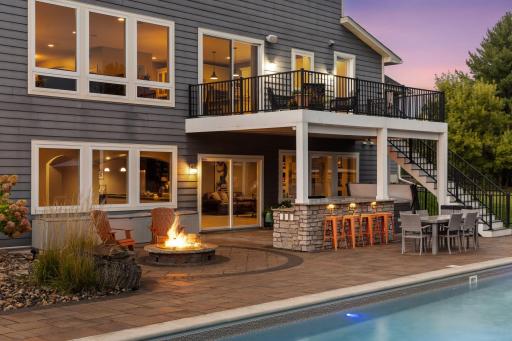 The backyard oasis at twilight is illuminated by the fire, pool and landscape lights.