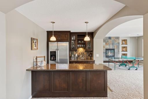 The lower level family room boasts three key spaces for entertaining - full bar, game room, and TV room with behind the couch elevated rail seating.