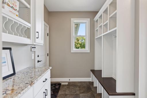 This efficient mudroom serves as the hub for organization with built in cubbies, a counter to stash keys and mail and an entrance to the garage as well as the backyard.