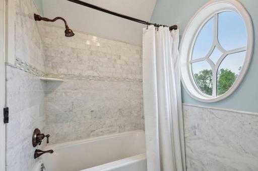 Upper-level full bathroom with marble tile surround bathtub and heated floors.