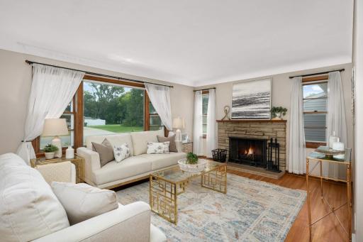 Large living room with fireplace is flooded with natural light