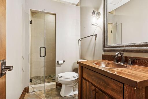 A beautifully designed bath featuring heated floors, rich finishes, and a copper sink that adds character.