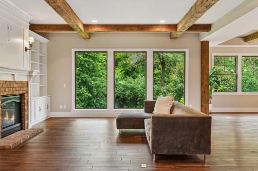 A place where comfort meets character, the great room features rich wood beams and expansive floor-to-ceiling windows that frame lush backyard views.