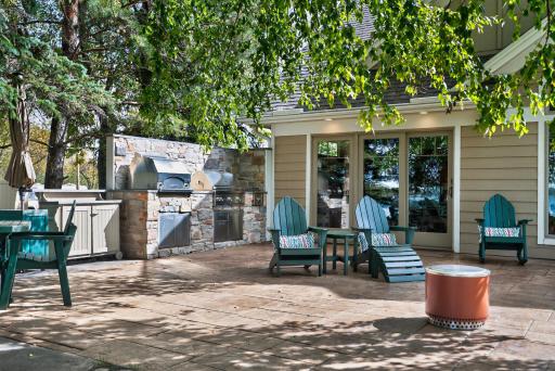 An expansive patio includes a fully equipped outdoor kitchen with a pizza oven, grill, and cooktop.