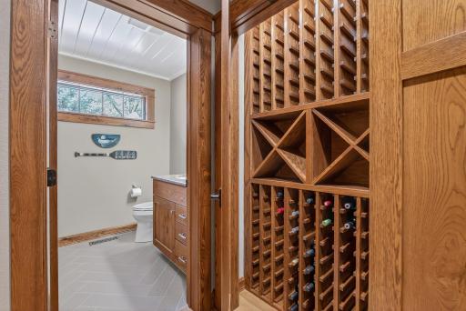 One closet in this area includes built-in wine storage for easy organization. A nearby three-quarter bath with tile floors and a walk-in shower is perfect for guests.