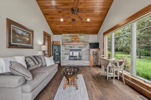 Connected to the suite is a private family room with tile flooring, a wood-paneled ceiling, a stone-surround wood-burning fireplace, and patio access, creating the perfect space to relax and unwind.