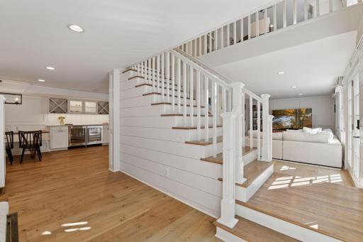 the cente stairway flanked in shiplap welcomes you to the Nantucket inspired lower level