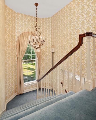The grand staircase ascends to the second floor landing which leads to four bedrooms and three baths.