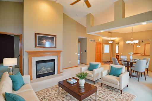 Bright open vaulted living room and dining room with a gas fireplace. Virtually staged.