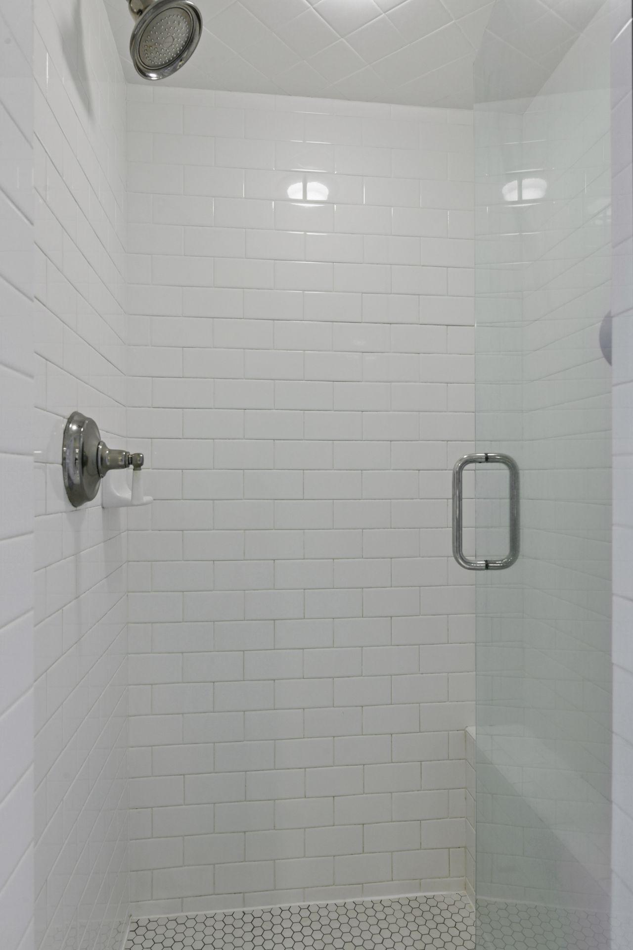 A subway tiled shower with built-in ledge and frameless glass enclosure completes this bathroom