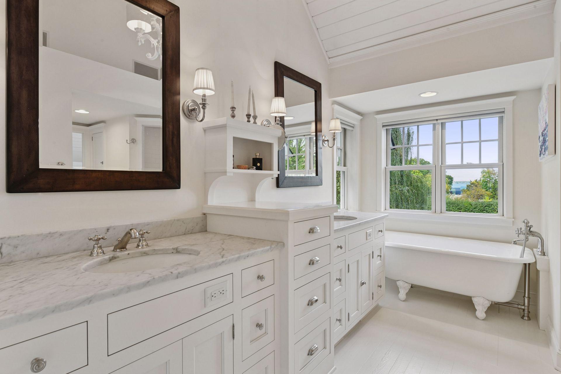 Your private spa! The Primary Bathroom features custom, comfort height cabinetry with marble countertops, a vaulted ceiling and a classic clawfoot bathtub.