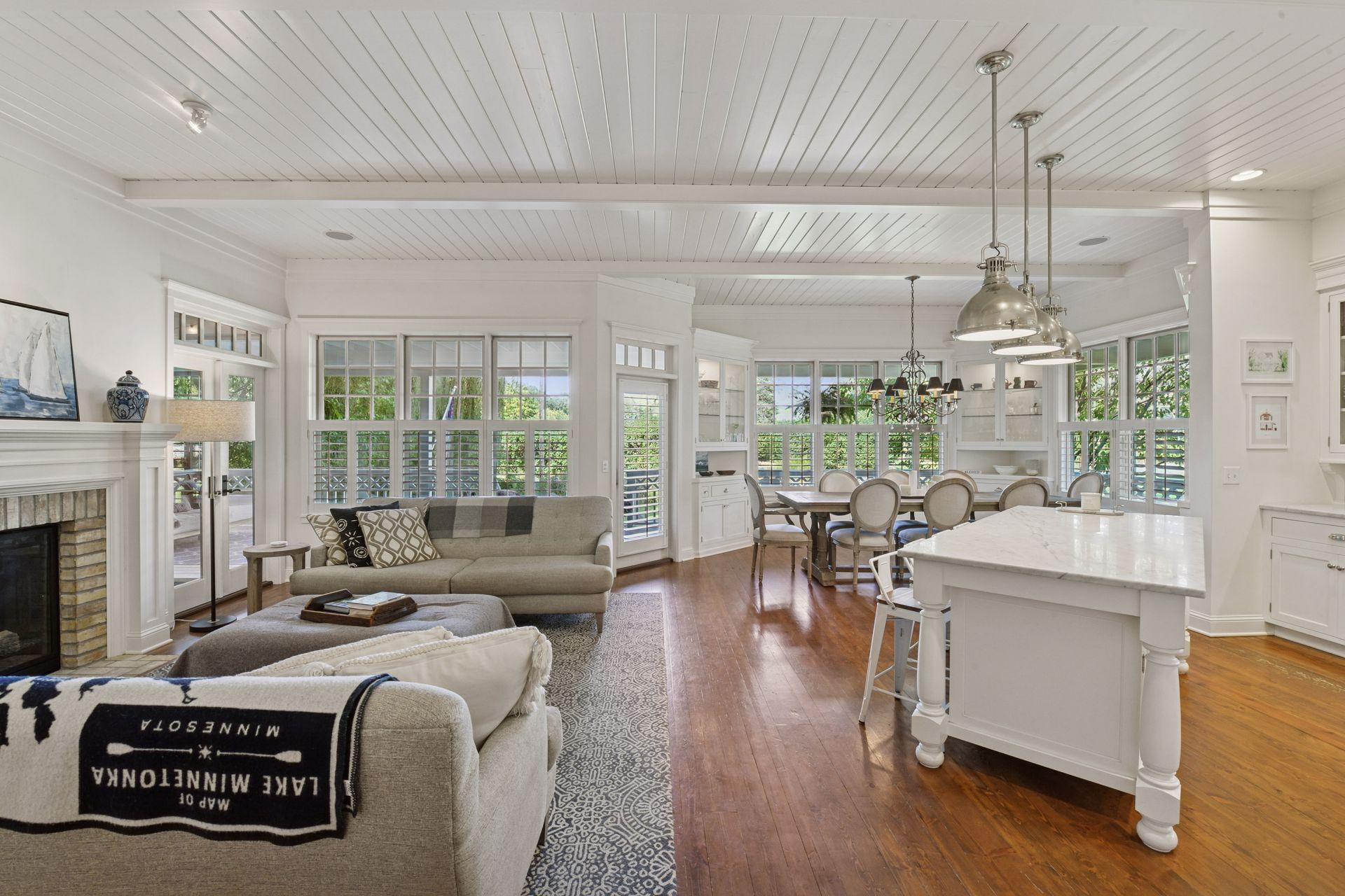 The open floor plan is bathed in natural light, framed by walls of windows and highlighted by enameled tongue-and-groove ceilings.