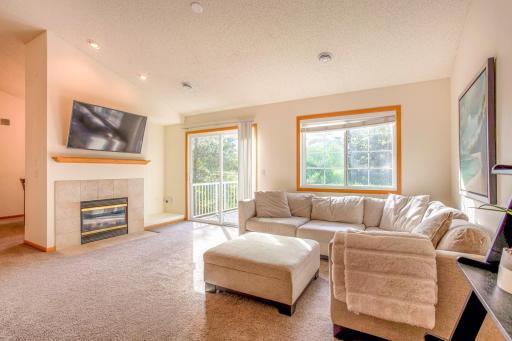 Bright and spacious living room with cozy gas fireplace, large windows, and direct access to the deck.