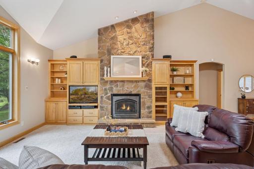 Gorgeous two story stone fireplace with built in shelving adds charm and functionality.