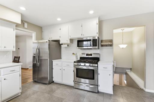 Kitchen with stainless steel appliances, including a gas range and microwave, positioned near access to the lower level for a practical layout.